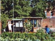 Gerard holding flag, with shed and annex of shed - Shed with sitting area, 