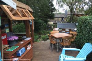 A view from the top of our garden looking towards the house. shows our dining table and the outside kitchen. It also shows the shutters made from an old shoe rack that gives shade on sunny days. of shed - Stables's Retreat, West Yorkshire